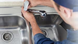 Plumber fixing kitchen sink faucet